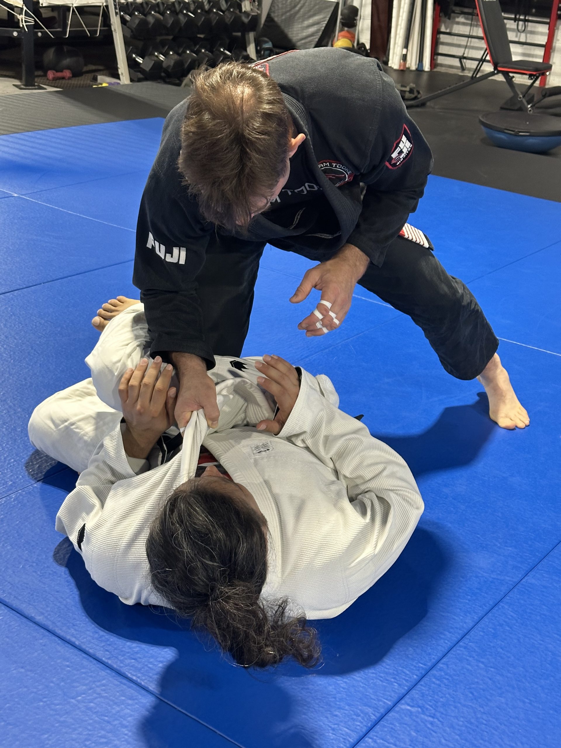 Travis Tooke grappling with a student on the mat